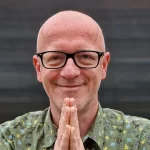 Harry zâmbește și ține mâinile în față. Curs instructor de Yoga Brașov.