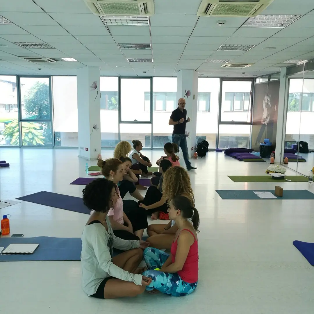 Curs Comunicare Instructori Yoga Brasov. Mai multe persoane stand jos fata in fata in 2 coloane facand un exercitiu de respiratie